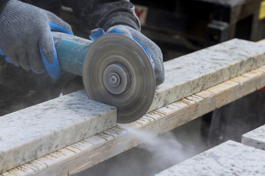 A skilled technician is measuring and cutting granite plate.