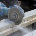 A skilled technician is measuring and cutting granite plate.