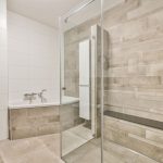 A spacious modern bathroom featuring a seamless glass shower door.